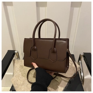 Detailed top view of a dark brown crossbody bag on a knit sweater and metal chair