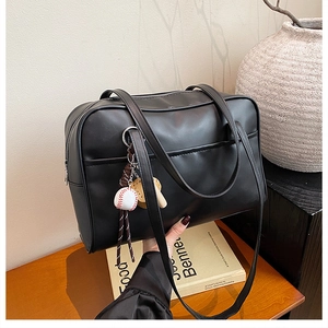 Close-up of black leather shoulder bag with baseball charm on a wooden table