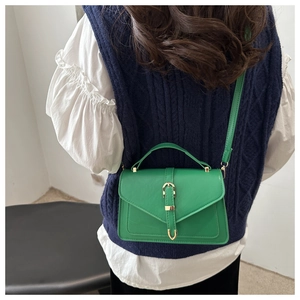 Detail of a bright green faux leather crossbody bag with a golden horseshoe buckle detail