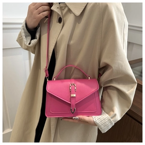Detailed view of a rose pink mini crossbody bag styled on a beige trench coat outfit
