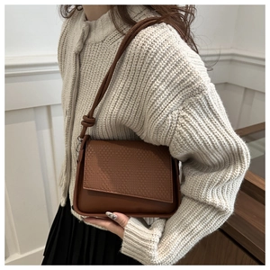 Close-up of brown PU leather shoulder bag with woven texture and side knot detail