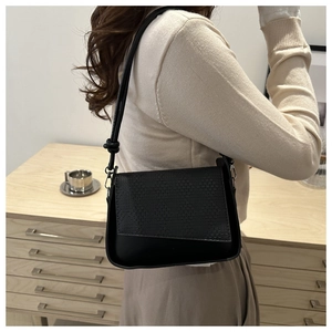 Detail of black crossbody bag with woven texture flap and knot strap decoration