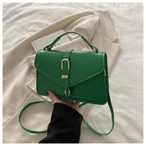 Detail of green leather crossbody bag with elegant gold U-shaped buckle and envelope flap