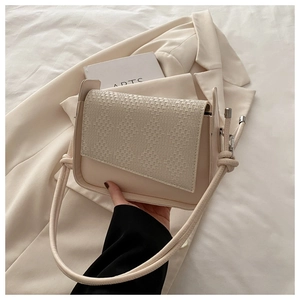 Detail of cream minimalist bag showing woven texture flap and smooth leather finish
