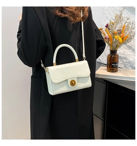 Détail du sac à bandoulière en cuir blanc avec grand fermoir rond doré et finitions