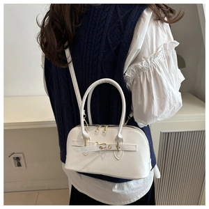 Detailed view of a white shell-shaped handbag with gold buckle and slim shoulder strap
