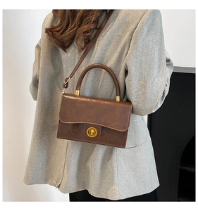 Dark brown vintage leather handbag with gold twist lock worn with a grey blazer