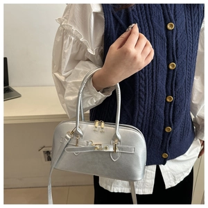 Detail of silver metallic boston bag with golden hardware and adjustable strap