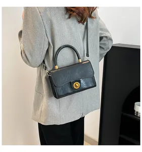 Détail du sac à main en cuir verni noir avec fermoir doré rotatif et fine bandoulière réglable