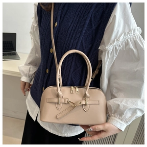 Detail of beige hobo bag with round handle and metal buckle strap on office background