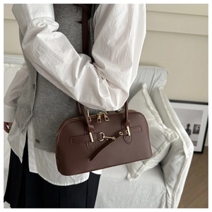 Close-up of a vintage dark brown leather handbag with gold metal buckle detail