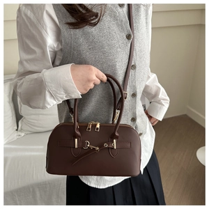 Detail of a brown leather bowling bag with gold hardware and a decorative belt buckle