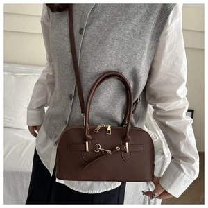 Detail of dark brown matte leather Boston bag with gold hardware on a model outfit