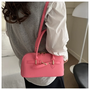 Detailed side view of pink faux leather shell bag with gold hardware and dual straps
