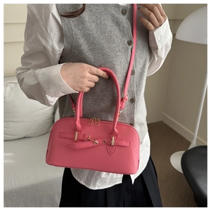 Close-up of bright pink faux leather handbag with gold metal ring and double zippers