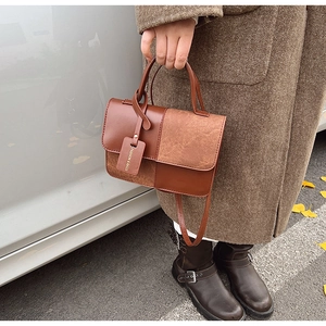 Detail of a brown patchwork crossbody bag featuring smooth leather and suede textures