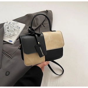 Detail of minimalist leather crossbody bag showing bicolor texture and fashion tag