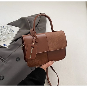 Detailed view of the brown textured faux leather and suede拼接 cross-body handbag