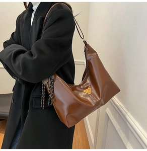 Detailed side view of brown glossy leather hobo bag featuring a triangle metal plate