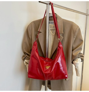 Macro detail of red glossy leather Hobo bag with triangular golden metal logo
