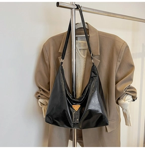 Close-up of black hobo shoulder bag with yellow triangle logo and glossy leather finish
