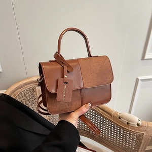 Vintage brown textured crossbody bag with top handle and fashion logo tag detail