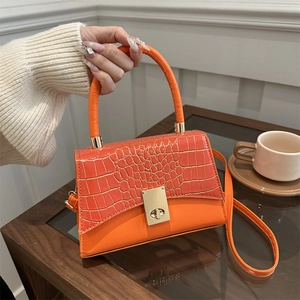 Orange crossbody handbag with crocodile pattern texture and golden swivel lock