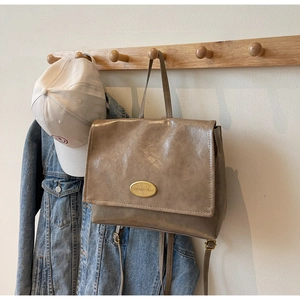 Brown vintage oil wax leather backpack hanging on wooden rack with lifestyle props