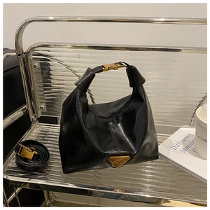 Détail du sac Hobo noir brillant avec logo triangle doré et boucle métallique sur l'anse