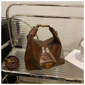 Détail du sac à bandoulière marron foncé rétro montrant le logo triangle en métal