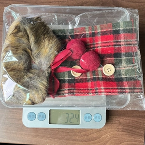Detail of red and green plaid wine bottle cover with faux fur trim and red pompoms