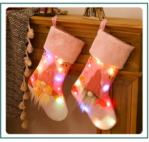 Detail of pink LED Christmas stockings with lighted gnome and sequins on a cozy mantel