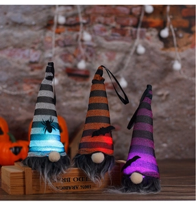 Close-up of three glowing Halloween gnomes with LED lights on a rustic wooden table