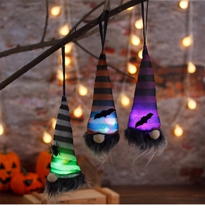 Close-up of three glowing Halloween gnome ornaments with LED lights and striped hats