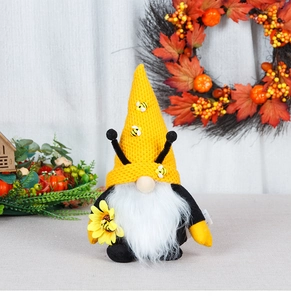 Detail of bee gnome plush with yellow knit hat, white beard, and sunflower accessory