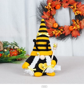 Close-up of a handmade bee gnome plush with striped hat and wooden honey dipper stick