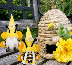 Paire de nains abeilles avec chapeaux jaunes et marguerites sur banc en bois