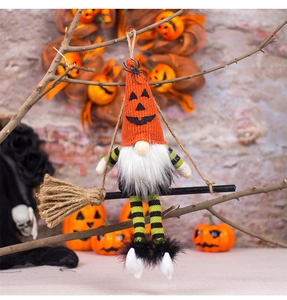 Close-up of a Halloween gnome on a wooden broom with striped legs and a pumpkin hat