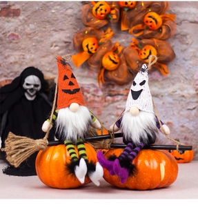Detail of two Halloween faceless gnomes on broomsticks with pumpkin bases for home decor