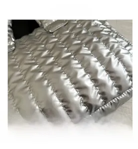 Macro shot of silver quilted puffer tote bag with glossy metallic finish texture