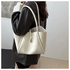 Dettaglio borsa tote color crema in ecopelle con fibbia oro su giacca di pelle