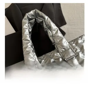 Detail of padded silver quilted handbag handles with metallic down-like texture