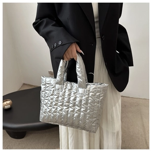 Close-up of a metallic silver quilted tote bag with horizontal stitching and soft padding