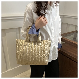 Detail of golden quilted tote bag with vertical stripes and metallic luster fabric