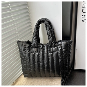 Detail of black quilted down tote bag with glossy finish and vertical stitching detail