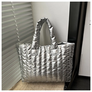 Close-up of quilted metallic silver puffer tote bag showing the padded texture and stitching