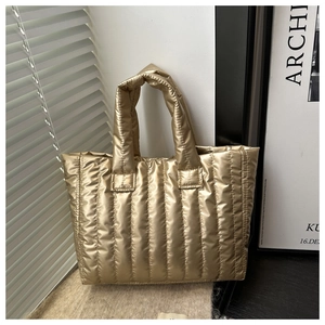 Detailed view of the gold puffer bag featuring vertical quilting and metallic glossy finish