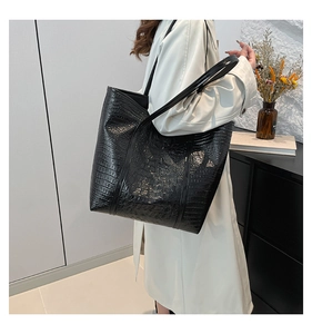 Detailed view of black crocodile pattern tote bag with high gloss finish and long straps
