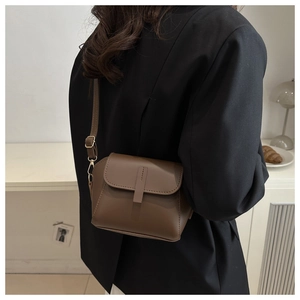 Detail of brown matte leather shoulder bag with vertical strap and gold metal buckle