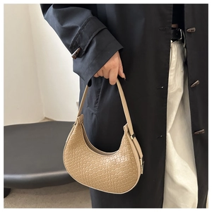 Detail of the woven texture and crescent shape of this beige faux leather shoulder bag